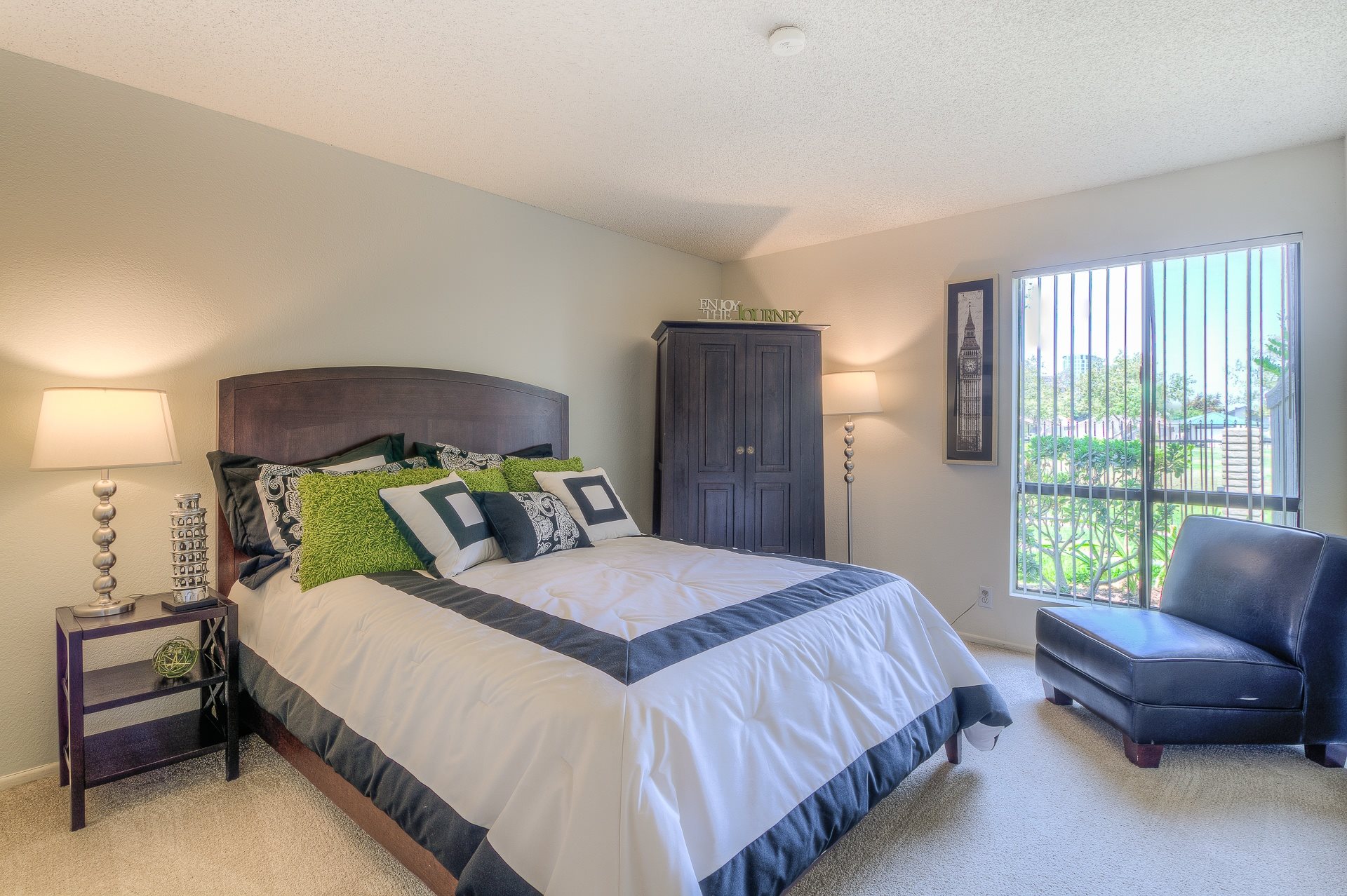 A bedroom with a large bed and a blue chair.,A bedroom with a large bed and a blue chair.